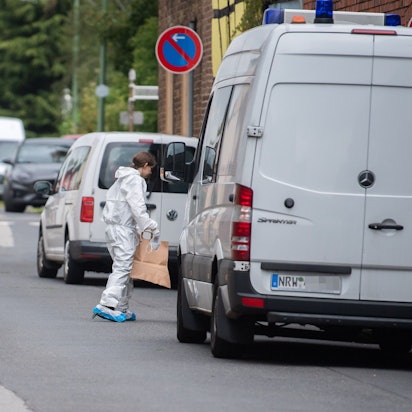 Ein Transporter der Polizei steht an der Straße, eine Frau im weißen Overall steht vor der Fahrertür.