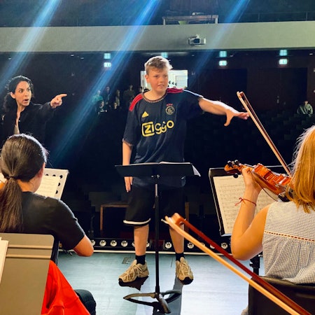 Konrad Adam und Bar Avni stehen vor dem Orchester und dirigieren gemeinsam.