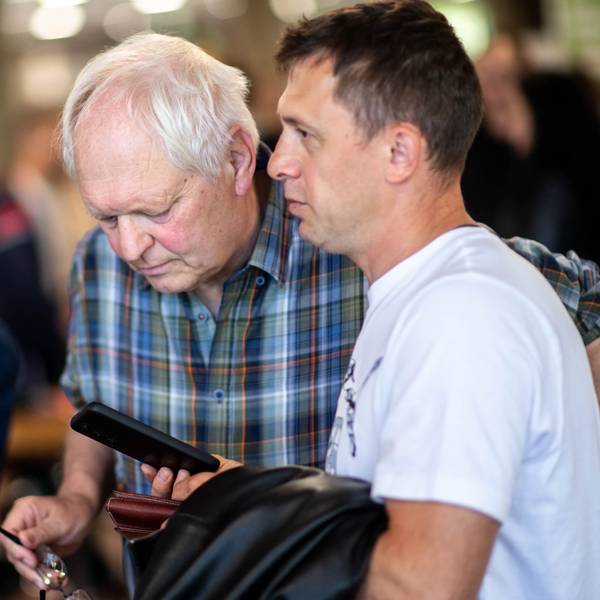 Das Bild zeigt Hans-Jürgen Lammers, wie auf das Smartphone eines Job-Suchenden schaut.
