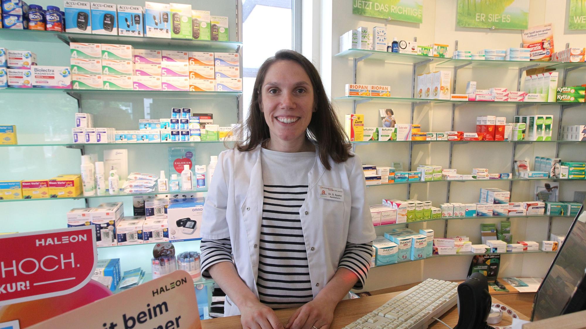 Eine Frau steht hinter der Theke einer Apotheke.