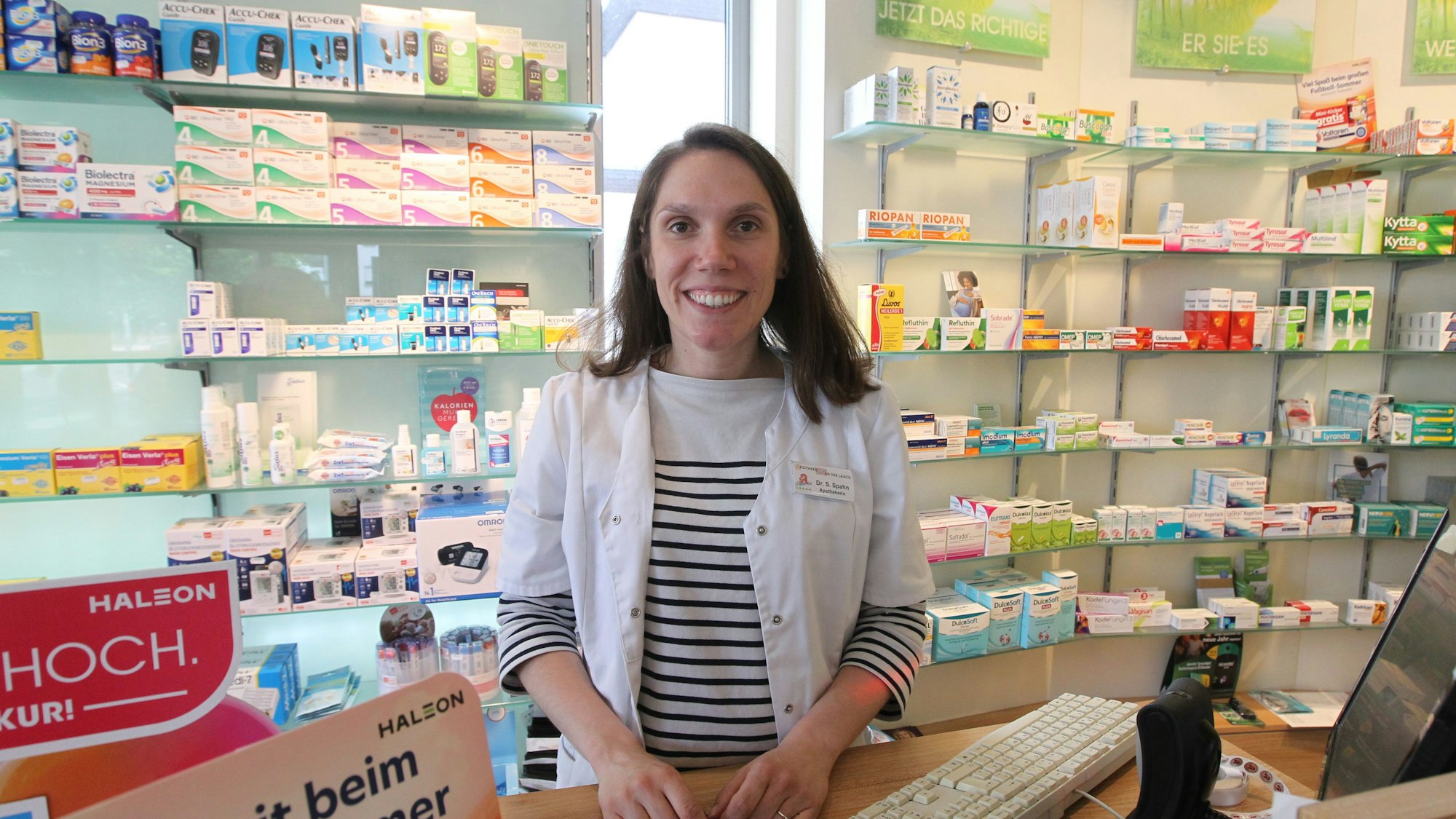 Eine Frau steht hinter der Theke einer Apotheke.