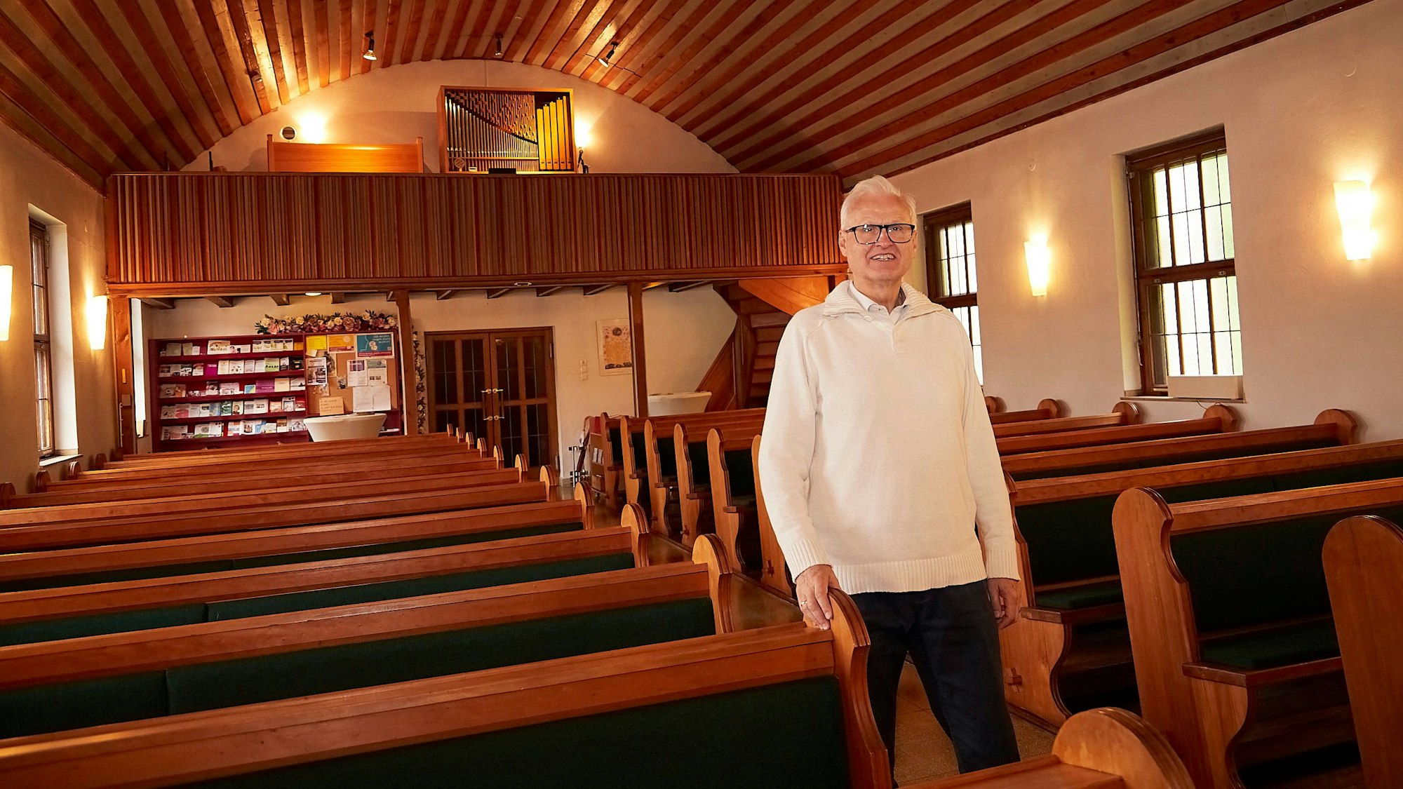 Pfarrer Christoph Cäsar geht durch den Mittelgang der evangelischen Kirche in Blankenheim. Rechts und links sind Bankreihen zu sehen, im Hintergrund die Orgel.