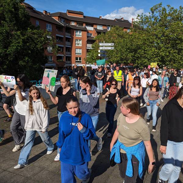 Ein Protestzug von Schülerinnen und Schülern mit Plakaten auf dem Plat vor dem Bürgerhaus.