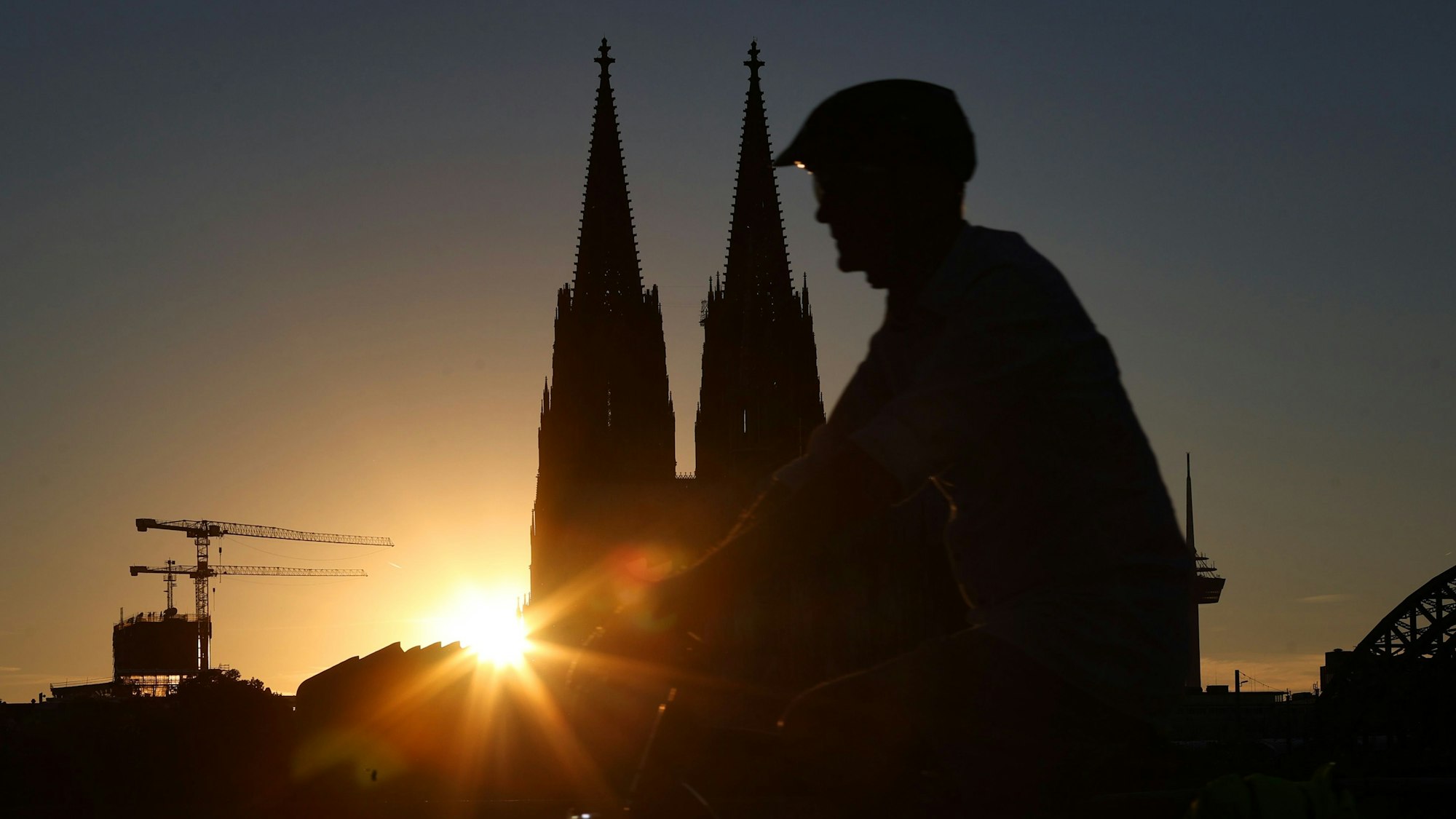 Sonnenuntergang am Rheinboulevard
mit Blick auf Dom
Fahrradfahrer im Vordergrund.
