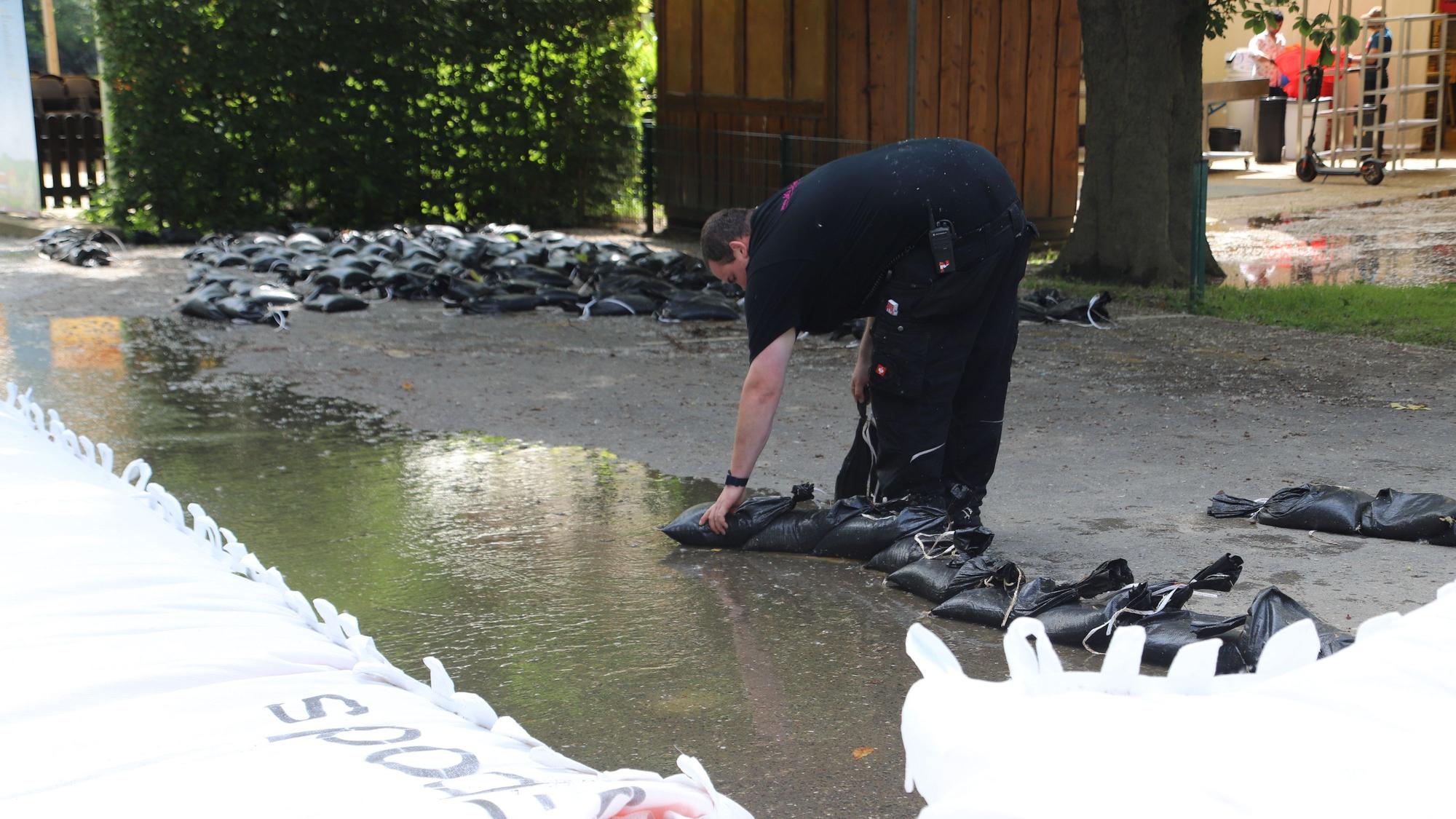 Ein Mitarbeiter von Langen baut einen kleinen Damm aus Sandsäcken zum Schutz vor dem abfließenden Wasser auf.