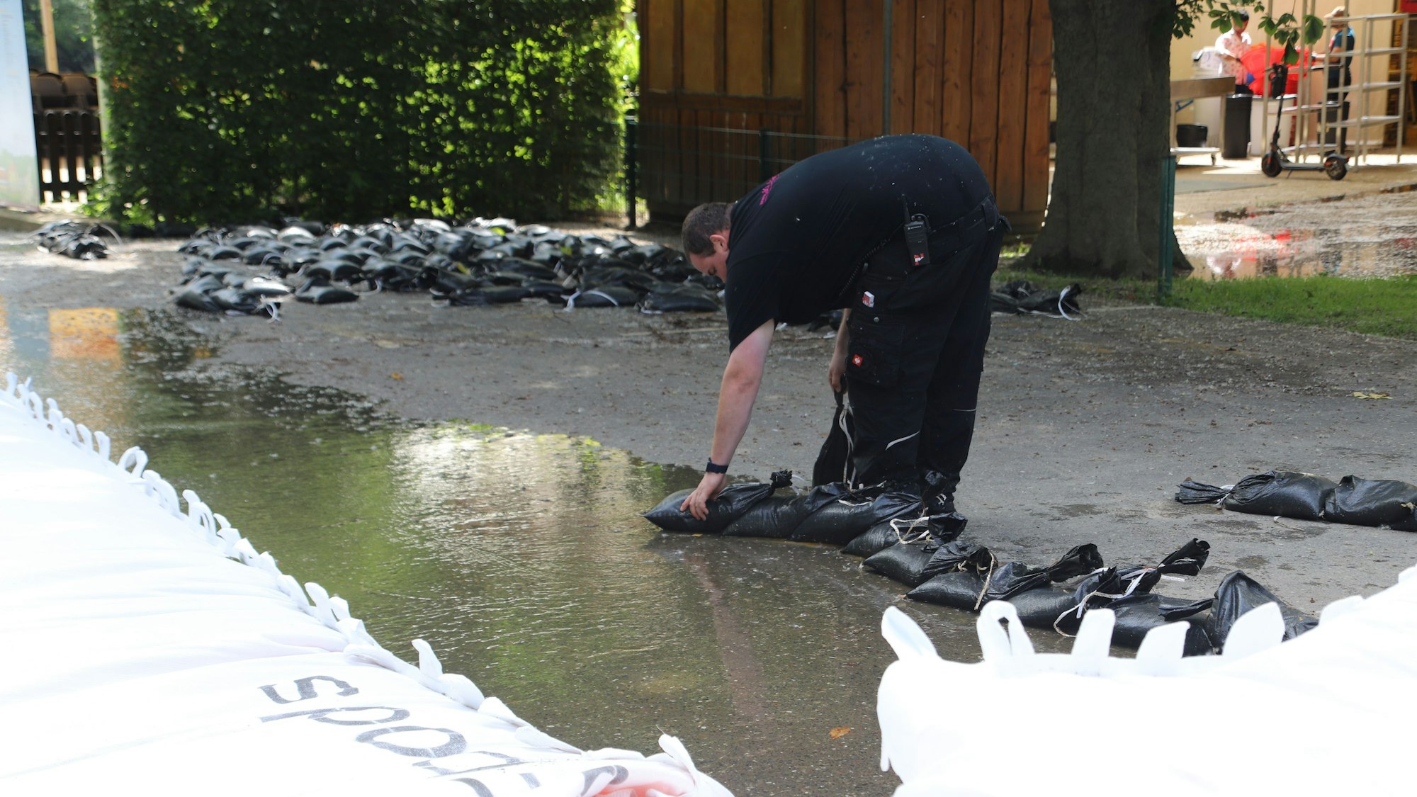 Ein Mitarbeiter von Langen baut einen kleinen Damm aus Sandsäcken zum Schutz vor dem abfließenden Wasser auf.