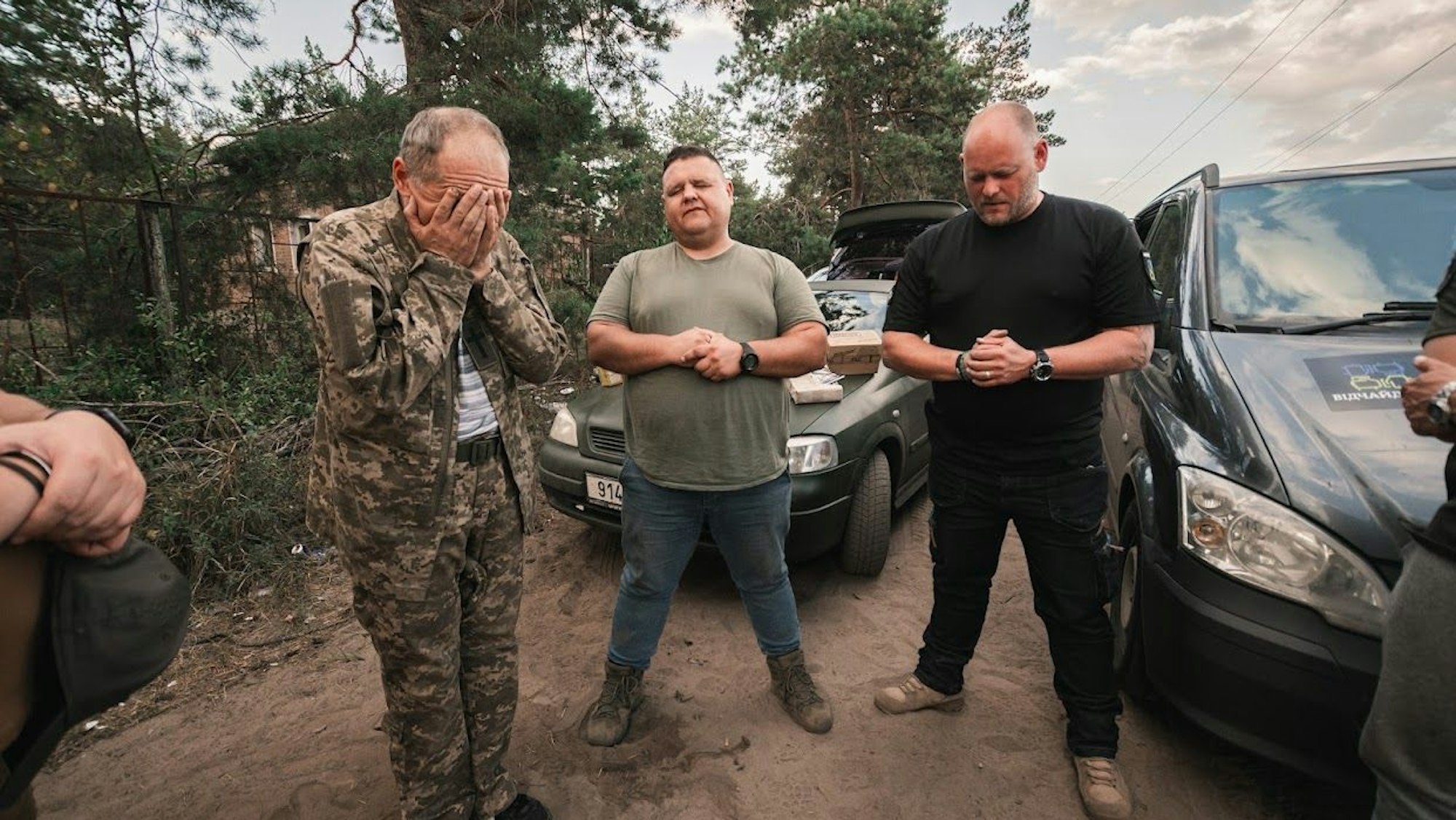 Mehrere Männer, einer in Militärkleidung, stehen in der Ukraine zusammen.