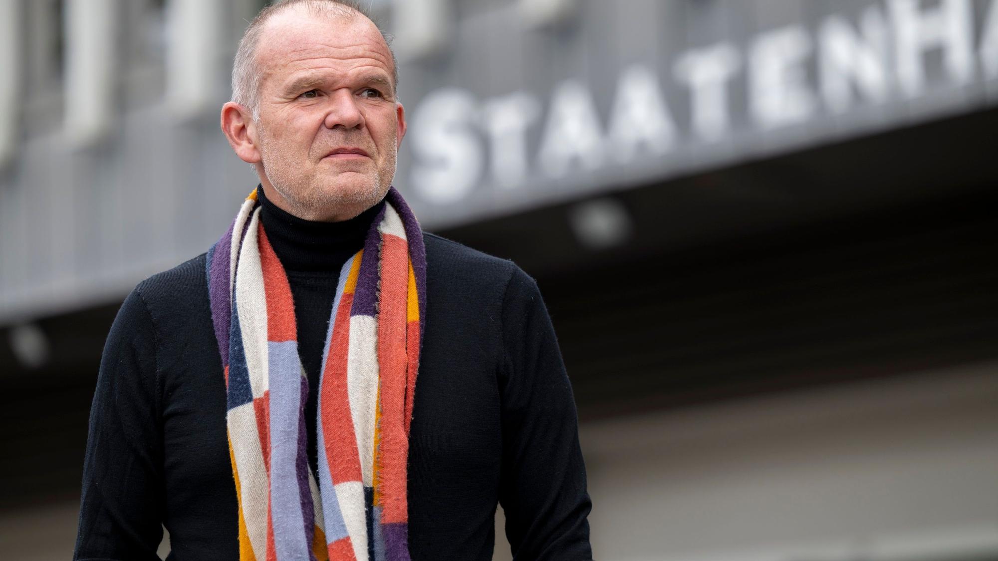 Francois-Xavier Roth, Generalmusikdirektor der Stadt Köln, steht vor dem Staatenhaus. Er trägt eine dunkle Jacke und einen gemusterten Schal.