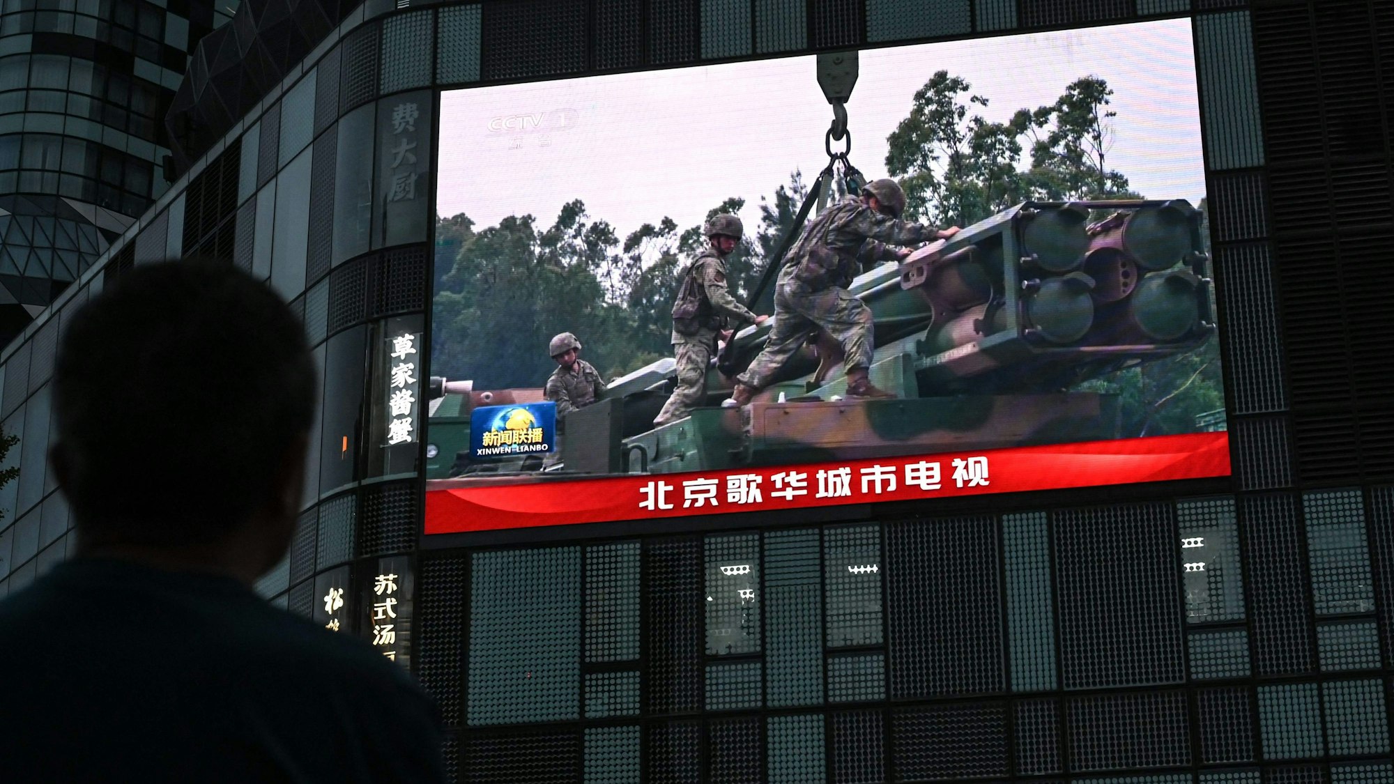 Ein Bildschirm zeigt in Peking Aufnahmen von Chinas Militärübung in der Nähe von Taiwan. China will Taiwan nach eigenen Angaben mit dem Manöver „bestrafen“.