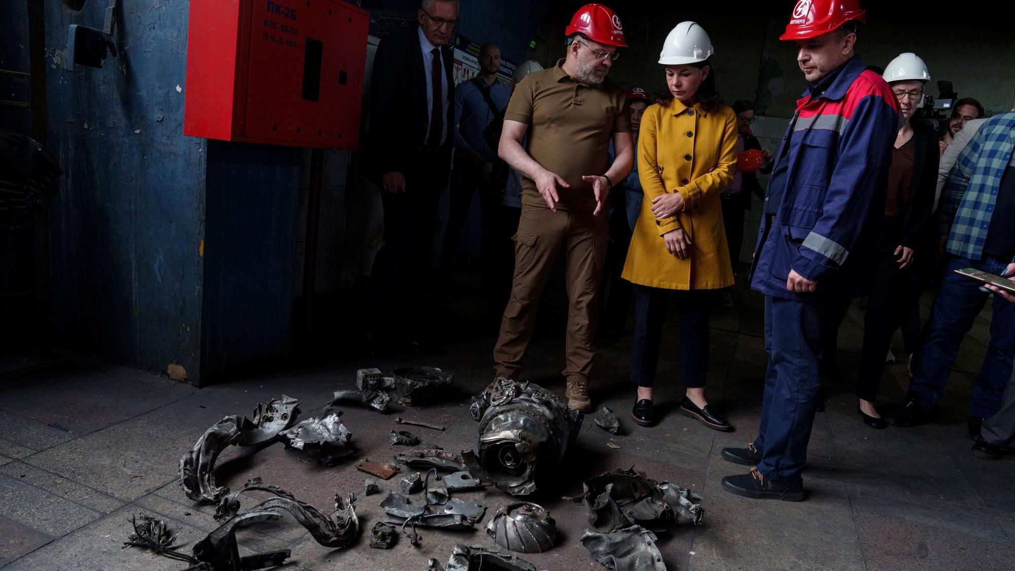 Annalena Baerbock und der ukrainische Energieminister Herman Haluschtschenko betrachten Fragmente einer russischen Rakete während eines offiziellen Besuchs in einem Wärmekraftwerk.