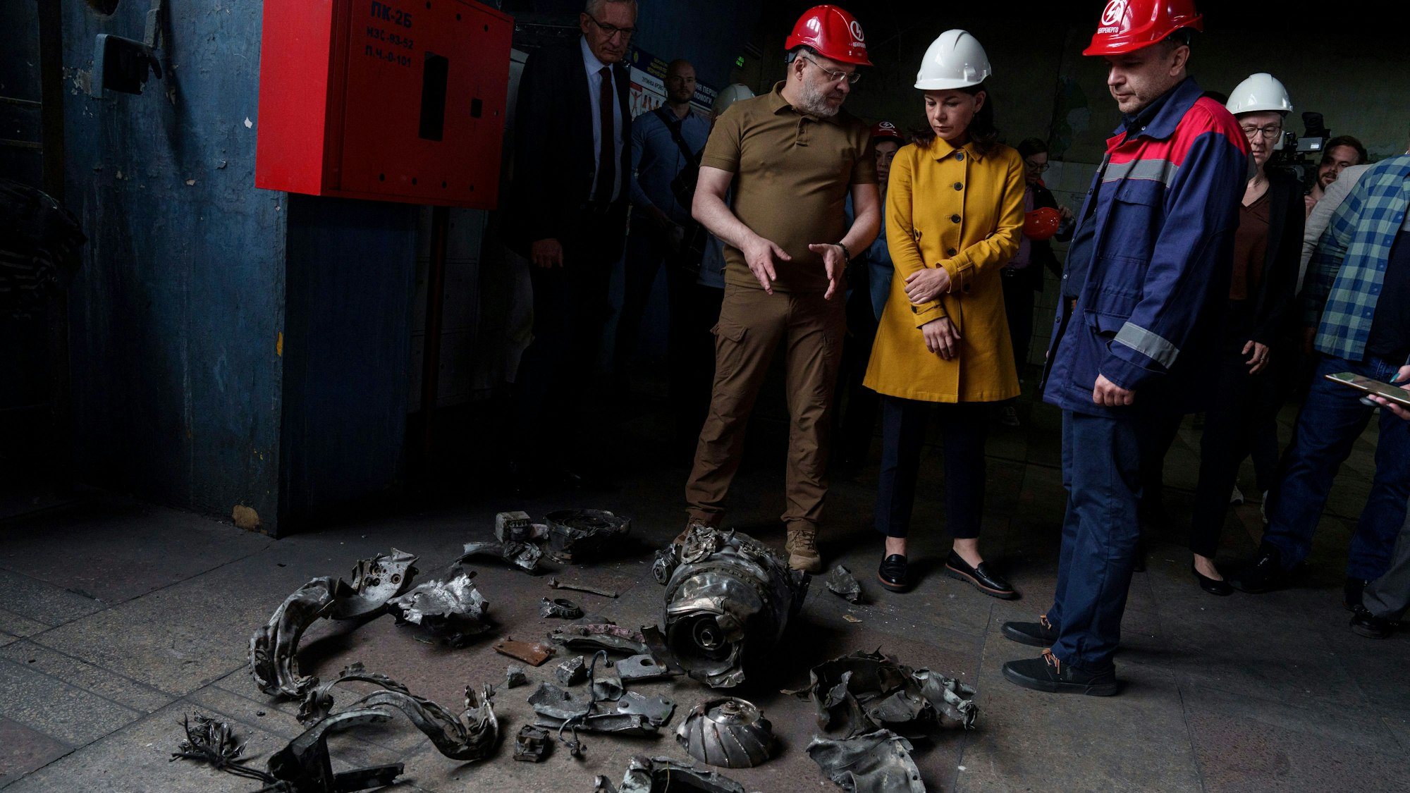 Annalena Baerbock und der ukrainische Energieminister Herman Haluschtschenko betrachten Fragmente einer russischen Rakete während eines offiziellen Besuchs in einem Wärmekraftwerk.