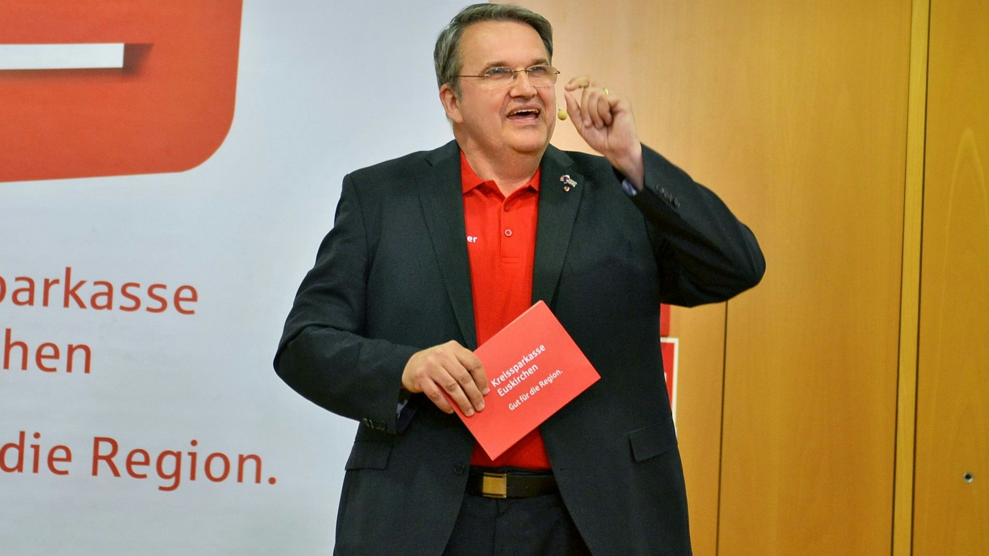 Udo Becker steht, ausgestattet mit einem Headset, auf der Bühne.