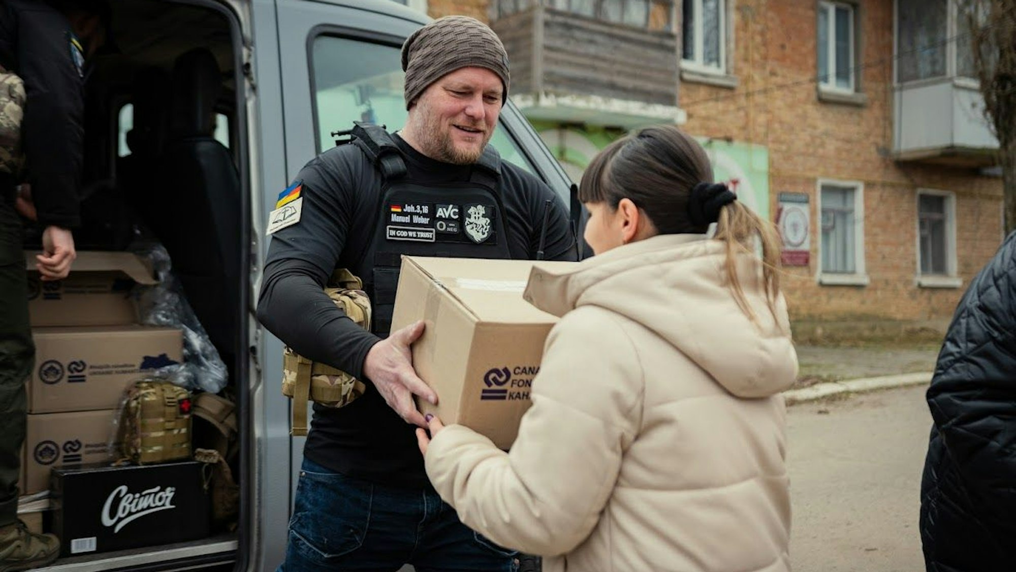 Ein Mann überreicht einer Frau ein Paket mit Hilfsgütern.