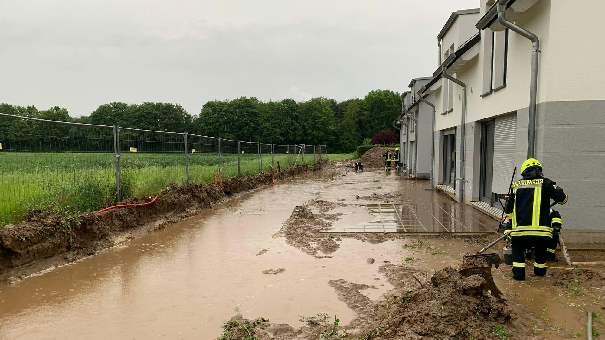 Feuerwehrleute befreien die Flächen hinter den Häusern an der Burgstraße vom Schlamm.