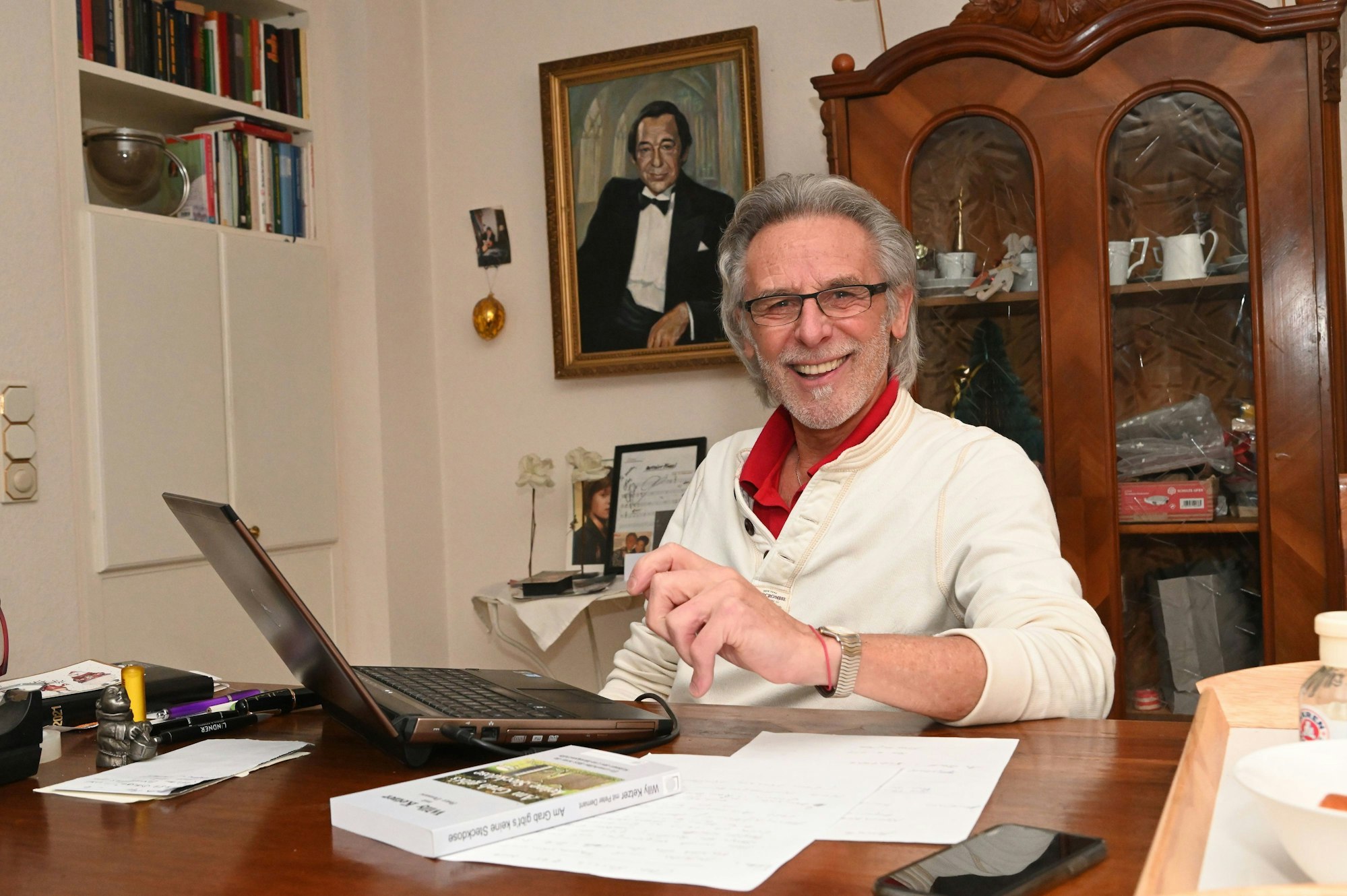 Musiker Willy Ketzer sitzt an einem Tisch vor einem Laptop