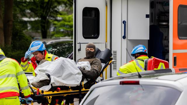 Ein verletzter Polizeibeamter wird vor einem Hochhaus in einen Krankenwagen gebracht.