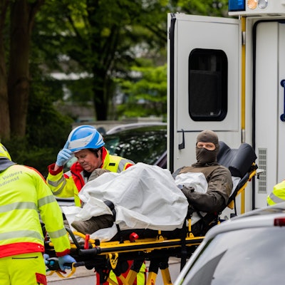 Ein verletzter Polizeibeamter wird vor einem Hochhaus in einen Krankenwagen gebracht.