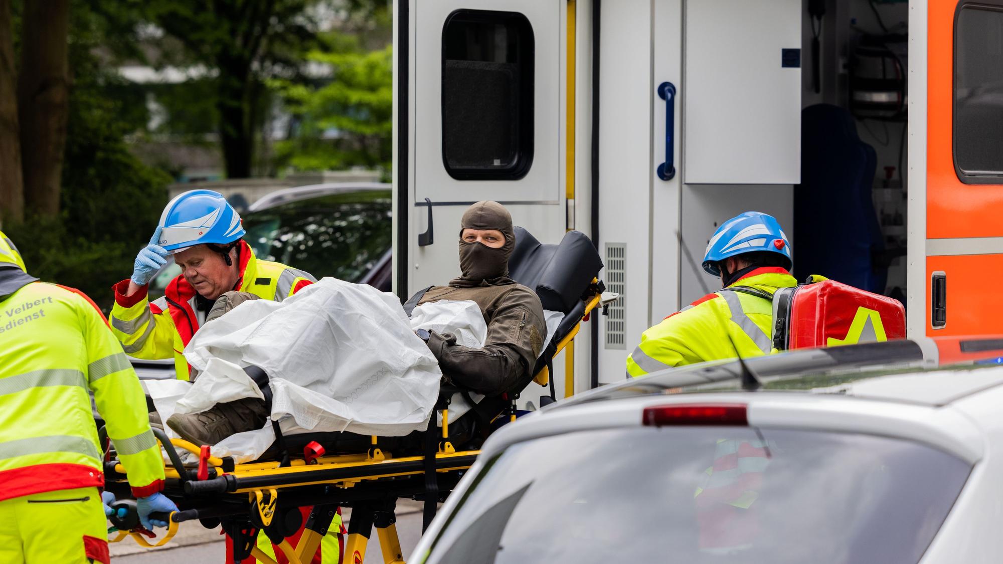 Ein verletzter Polizeibeamter wird vor einem Hochhaus in einen Krankenwagen gebracht.
