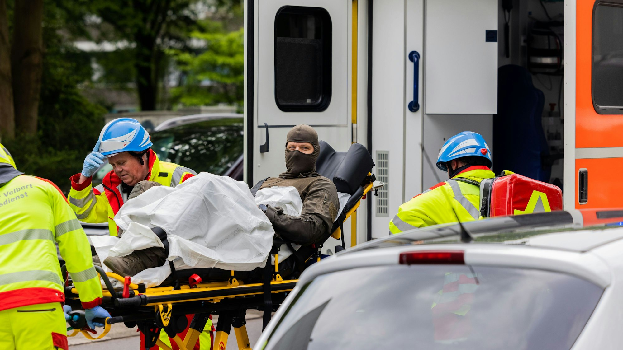 Ein verletzter Polizeibeamter wird vor einem Hochhaus in einen Krankenwagen gebracht.