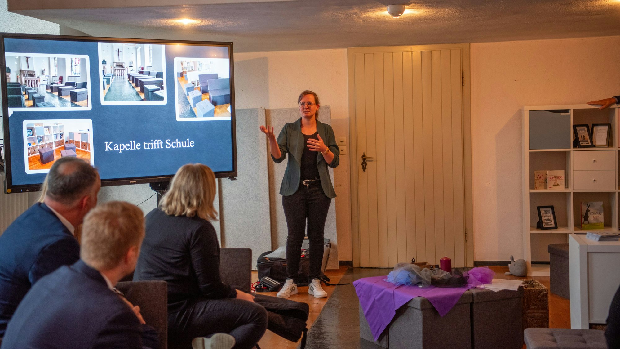 Seelsorgerin Vanessa Grbavac steht vor einer Multimediawand in der neuen Kapelle auf der Fotos gezeigt werden.