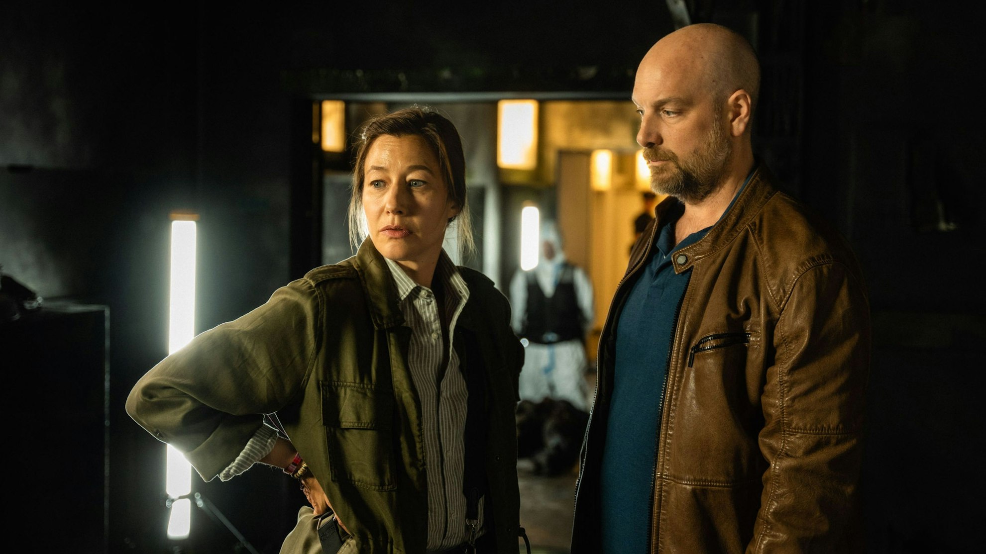 Im Mittelpunkt des Bildes stehen die beiden Ermittler Blohm und Eden vor der dunklen Kulisse des abgebrannten Gebäudes.