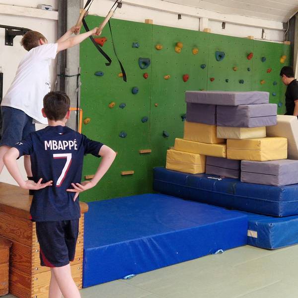 Drei Jungen hängen an Seilen und klettern auf Sportmatten im Kölner Thearapiezentrum.