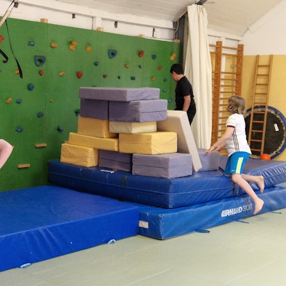 Drei Jungen hängen an Seilen und klettern auf Sportmatten im Kölner Thearapiezentrum.