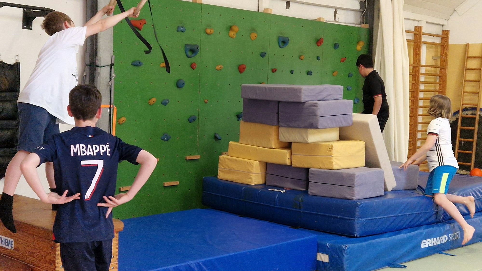 Drei Jungen hängen an Seilen und klettern auf Sportmatten im Kölner Thearapiezentrum.