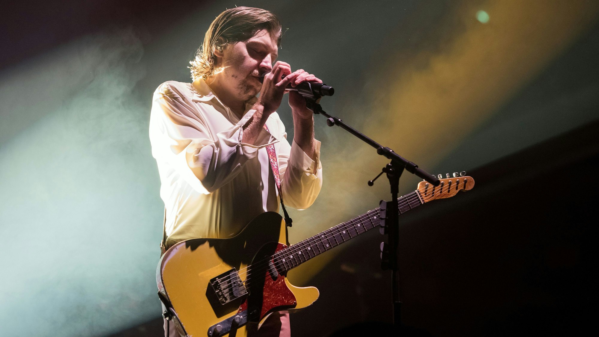 Philipp Poisel mit Gitarre singt in ein Mikrofon.