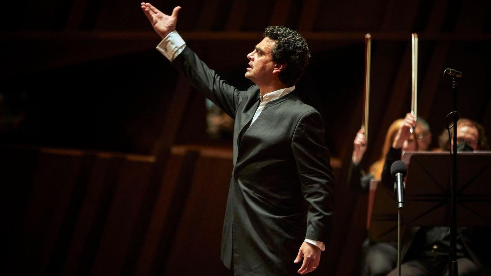 Rolando Villazón als Tenor während der Aufführung, elegant in schwarzem Anzug gekleidet und mit erhobener rechter Hand.