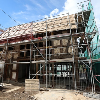 Ein Fachwerkhaus, an dem die meisten Balken freistehen und die Gefache fehlen, ist eingerüstet.