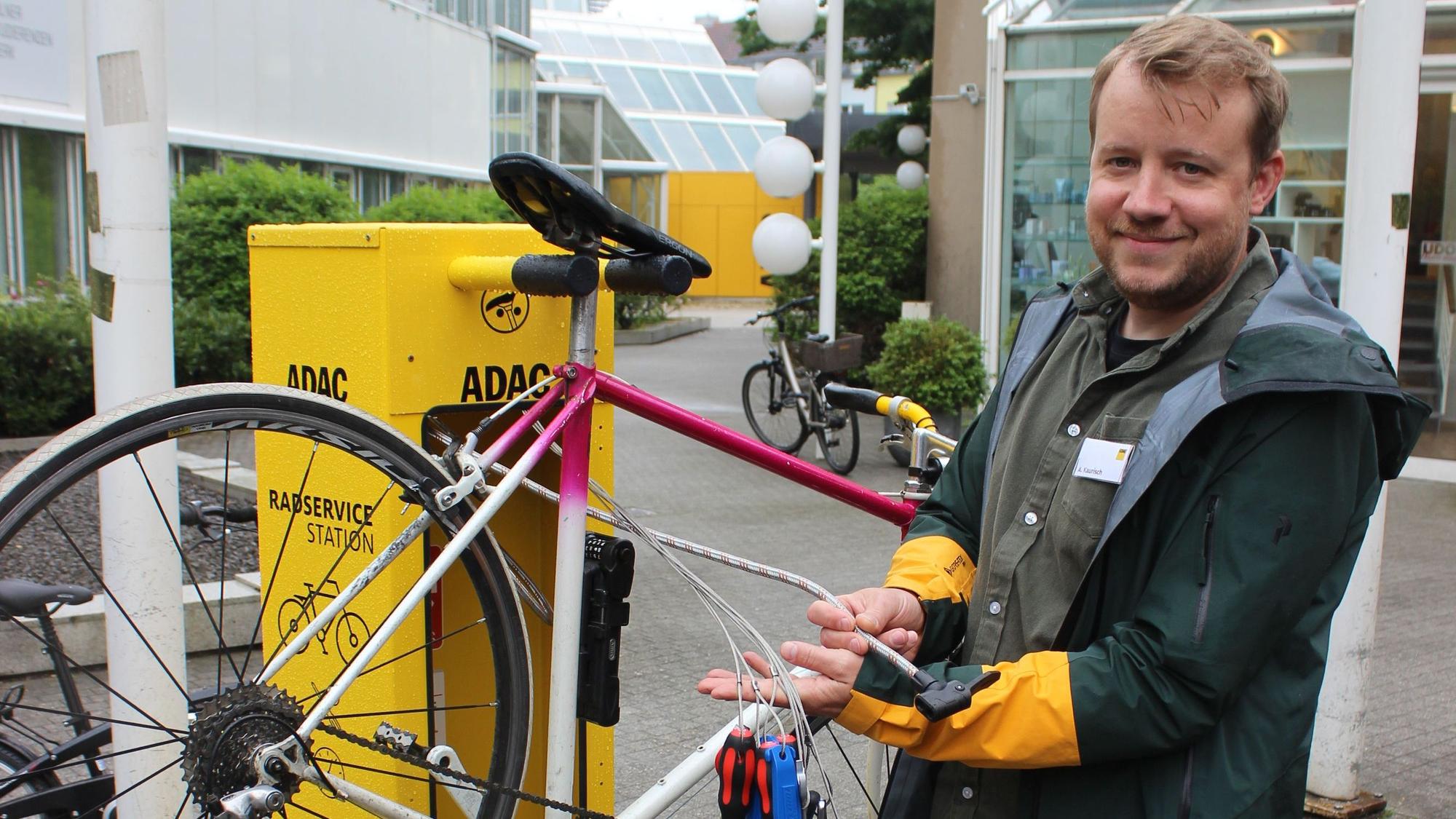 Zu sehen ist ein Mann, der verschiedene Werkzeuge, wie zum Beispiel Inbus-Schlüssel und Schraubendreher, die für eine Fahrrad-Reparatur benötigt werden, in den Händen hält.