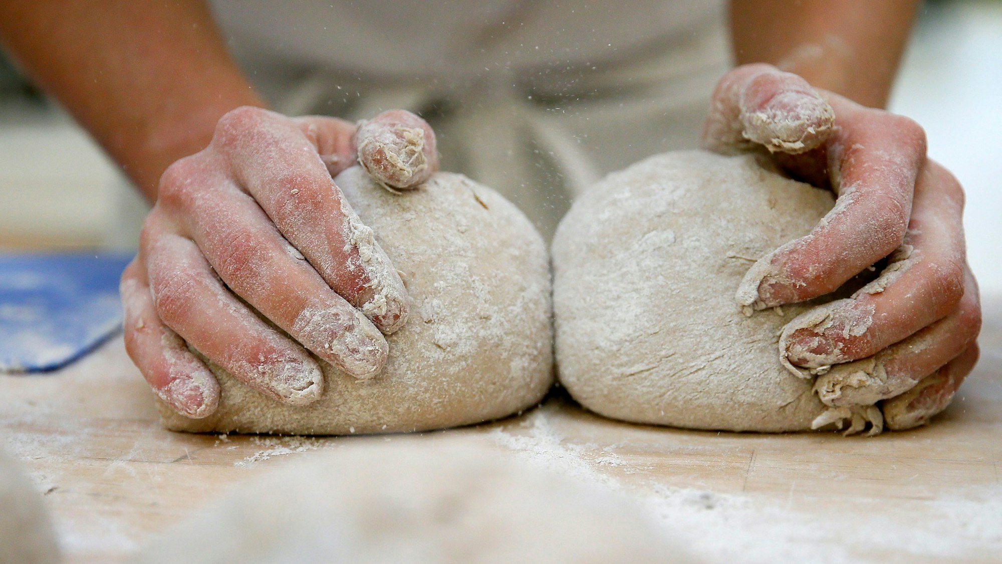 Zwei Hände kneten einen Teig.