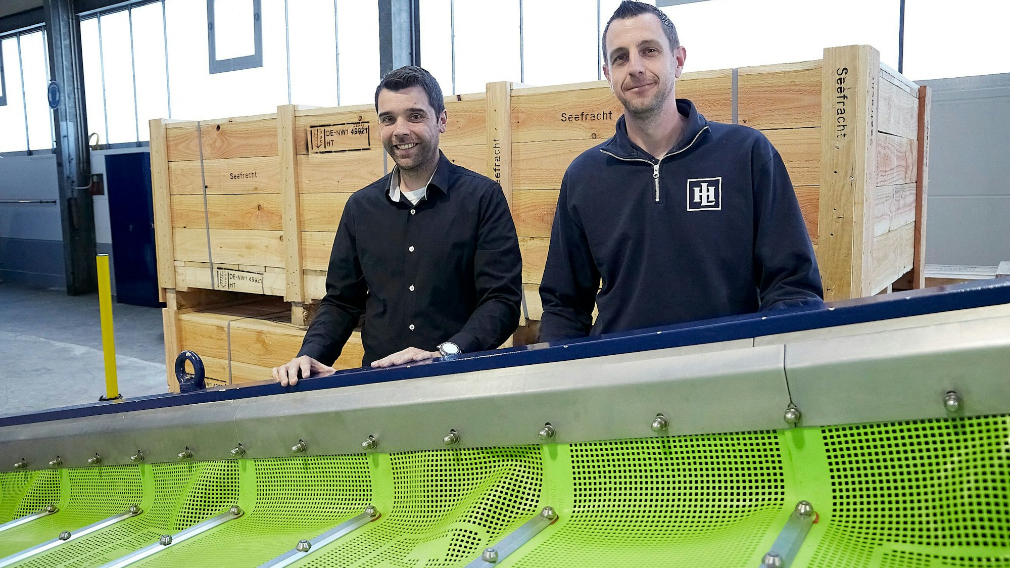 Zwei Männer, Jens Hecker (links) und Sven Heinen, stehen an einem der Produkte der Firma Hein, Lehmann, die unter anderem Siebtechnik für die Industrie herstellt.