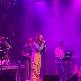 Ein Band mit Jugendlichen steht auf einer Bühne und macht Musik.