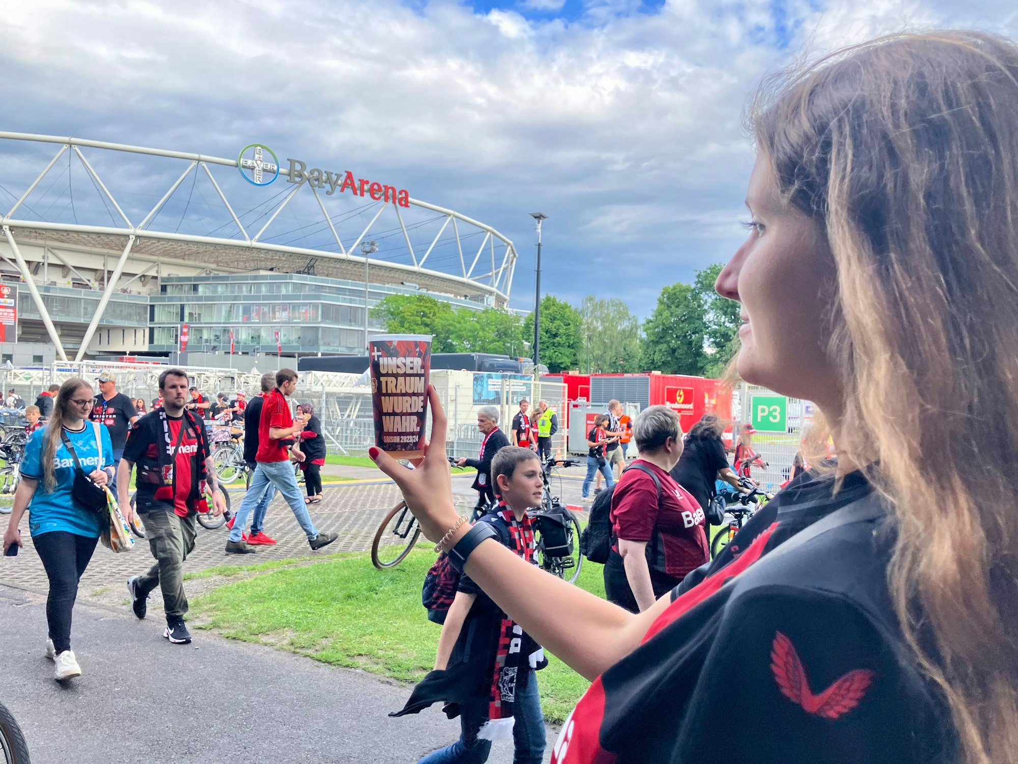 Dass Franziska Busse die Bay-Arena heute nur von außen fotografieren kann, macht ihr nichts: „Das war eine richtig entspannte Stimmung heute rund ums Stadion. Wir haben die Mannschaft erst am Schloss Morsbroich mit empfangen und dann den Autokorso hier herbegleitet“, erzählt sie auf dem Fan-Fest unter der Stelze. Dafür war sie gestern dabei, beim historischen Double-Sieg live im Olympiastadion in Berlin.