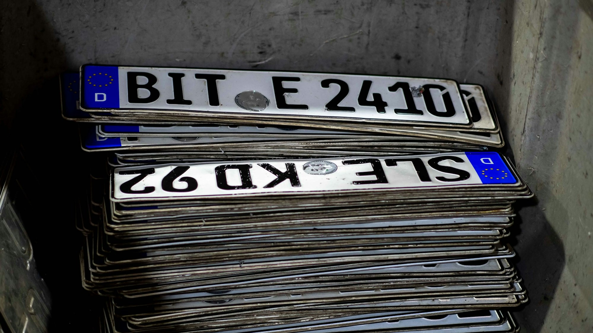 Alte Kfz-Kennzeichen liegen gestapelt in einem Behälter.