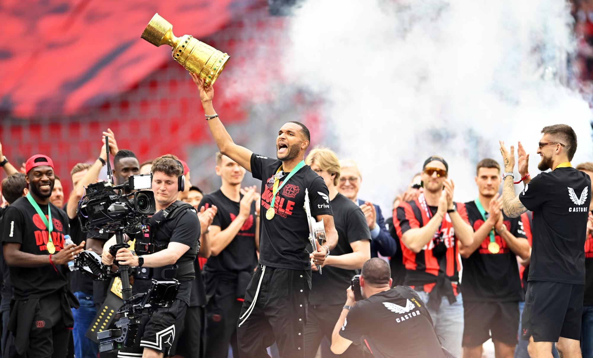 Leverkusens Jonathan Tah (M) präsentiert bei der Meisterfeier in der BayArena die Meisterschale und den Pokal.