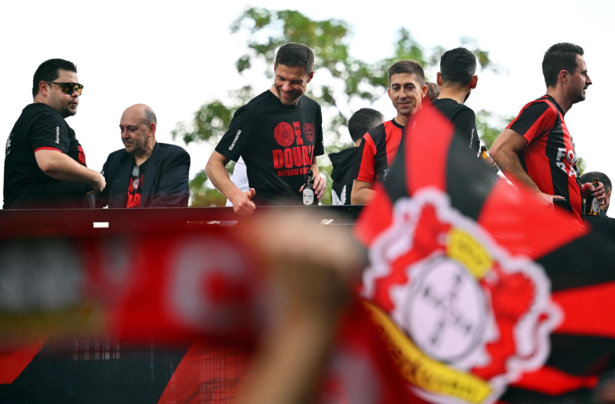 Leverkusens Trainer Xabi Alonso (M) und seine Spieler fahren bei einem Autokorso von Schloss Morsbroich zur BayArena in einem offenen Bus durch die Stadt.