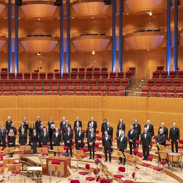 Die Mitglieder des KölnChor haben sich auf der Bühne der Kölner Philharmonie aufgestellt. Sie tragen schwarz.