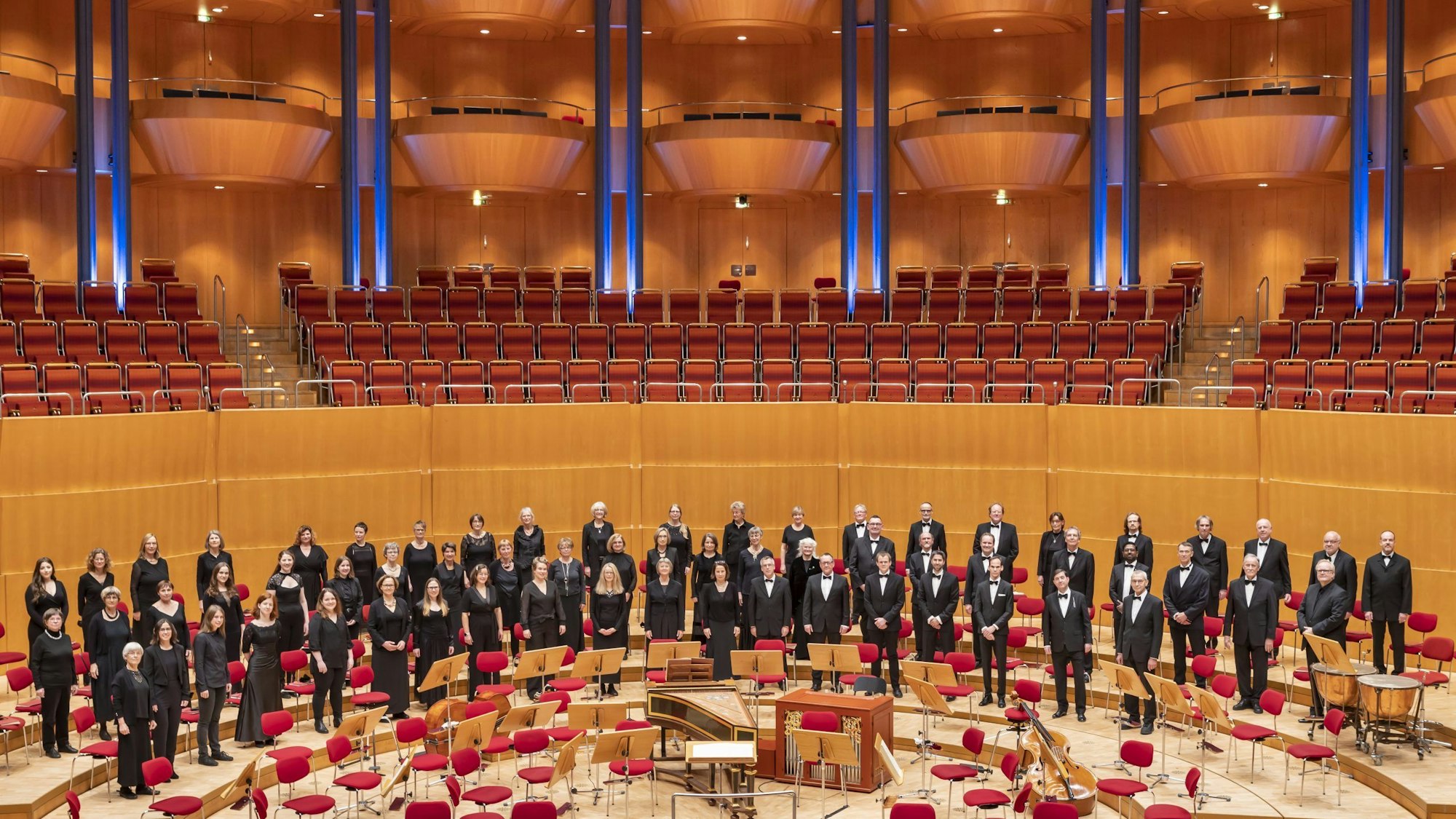 Die Mitglieder des KölnChor haben sich auf der Bühne der Kölner Philharmonie aufgestellt. Sie tragen schwarz.