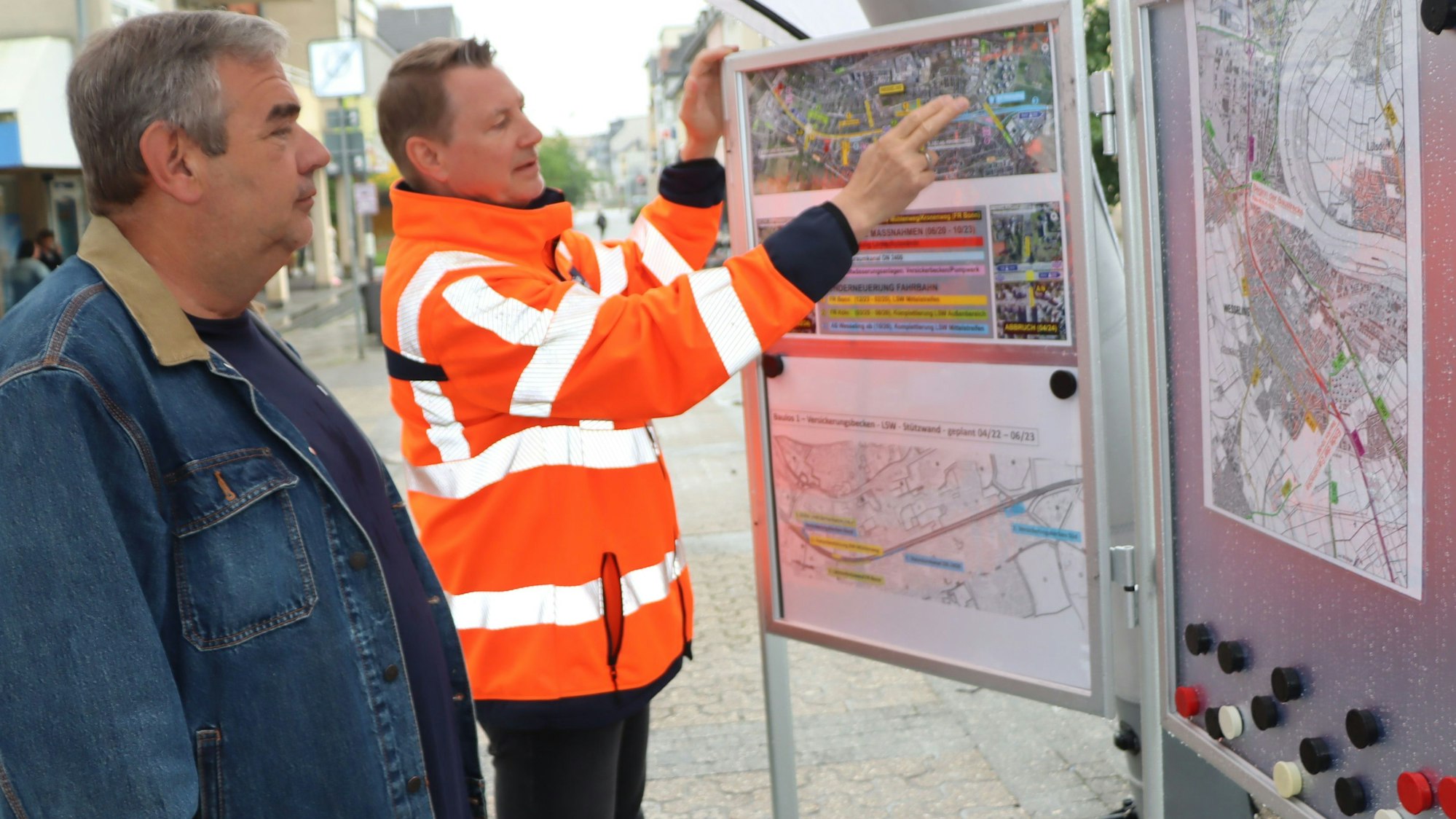 Zu sehen ist Helge Wego, der einem Bürger einen Bauplan erläutert.