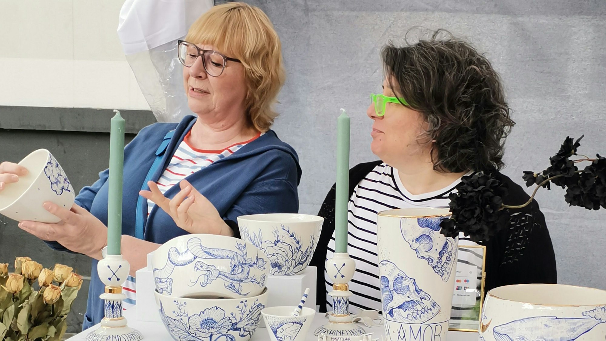 Zu sehen sind zwei Frauen, die Keramik betrachten.