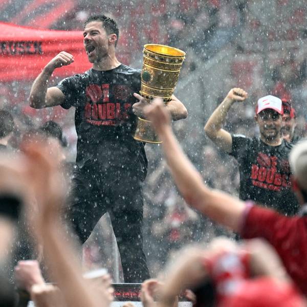Bayer Leverkusen's Spanish head coach Xabi Alonso holds the German cup (DFB Pokal) trophy as he celebrates with his team and their fans their victories in the German cup (DFB pokal) and German Bundesliga at the BayArena stadion in Leverkusen, western Germany, on May 26, 2024. Bayer Leverkusen became the first team in the Bundesliga history to go through an entire season unbeaten. (Photo by Roberto Pfeil / AFP)
