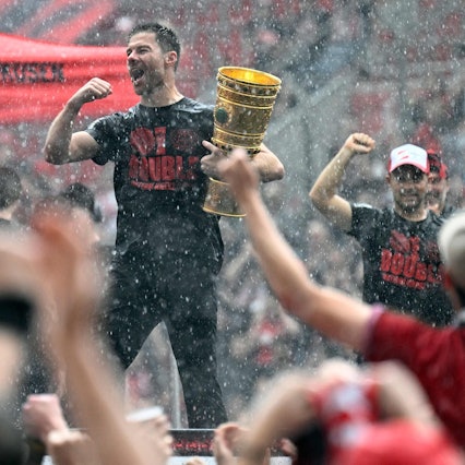 Bayer Leverkusen's Spanish head coach Xabi Alonso holds the German cup (DFB Pokal) trophy as he celebrates with his team and their fans their victories in the German cup (DFB pokal) and German Bundesliga at the BayArena stadion in Leverkusen, western Germany, on May 26, 2024. Bayer Leverkusen became the first team in the Bundesliga history to go through an entire season unbeaten. (Photo by Roberto Pfeil / AFP)