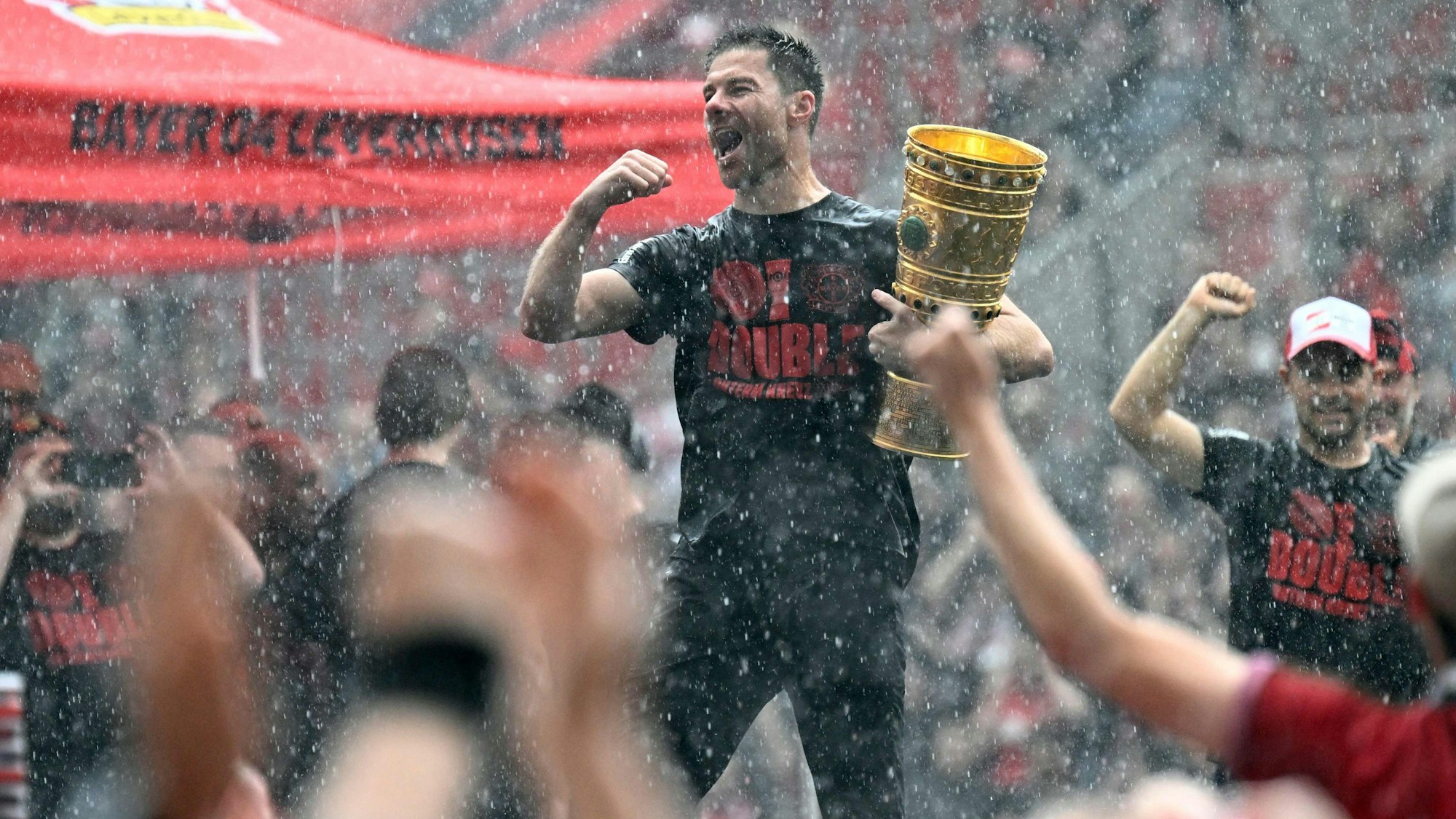 Bayer Leverkusen's Spanish head coach Xabi Alonso holds the German cup (DFB Pokal) trophy as he celebrates with his team and their fans their victories in the German cup (DFB pokal) and German Bundesliga at the BayArena stadion in Leverkusen, western Germany, on May 26, 2024. Bayer Leverkusen became the first team in the Bundesliga history to go through an entire season unbeaten. (Photo by Roberto Pfeil / AFP)