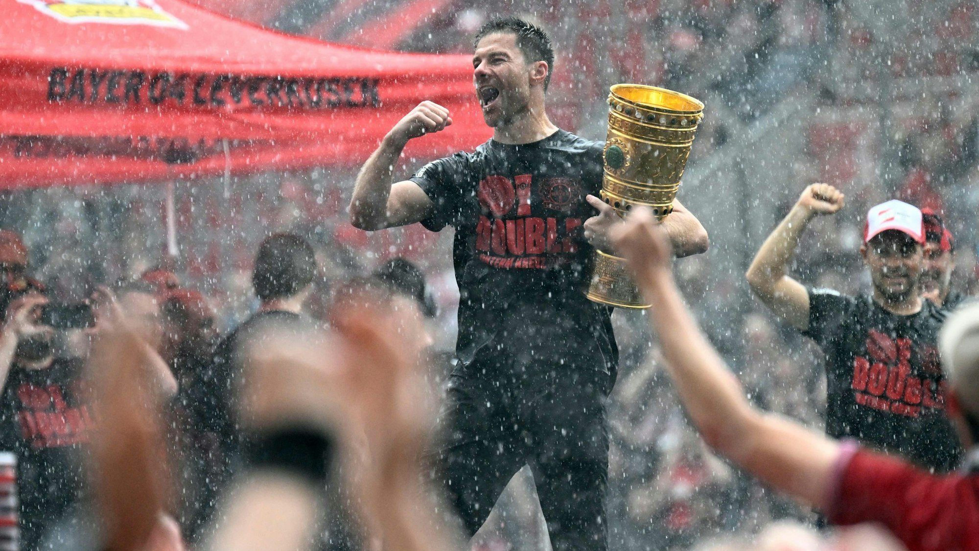 Bayer Leverkusen's Spanish head coach Xabi Alonso holds the German cup (DFB Pokal) trophy as he celebrates with his team and their fans their victories in the German cup (DFB pokal) and German Bundesliga at the BayArena stadion in Leverkusen, western Germany, on May 26, 2024. Bayer Leverkusen became the first team in the Bundesliga history to go through an entire season unbeaten. (Photo by Roberto Pfeil / AFP)