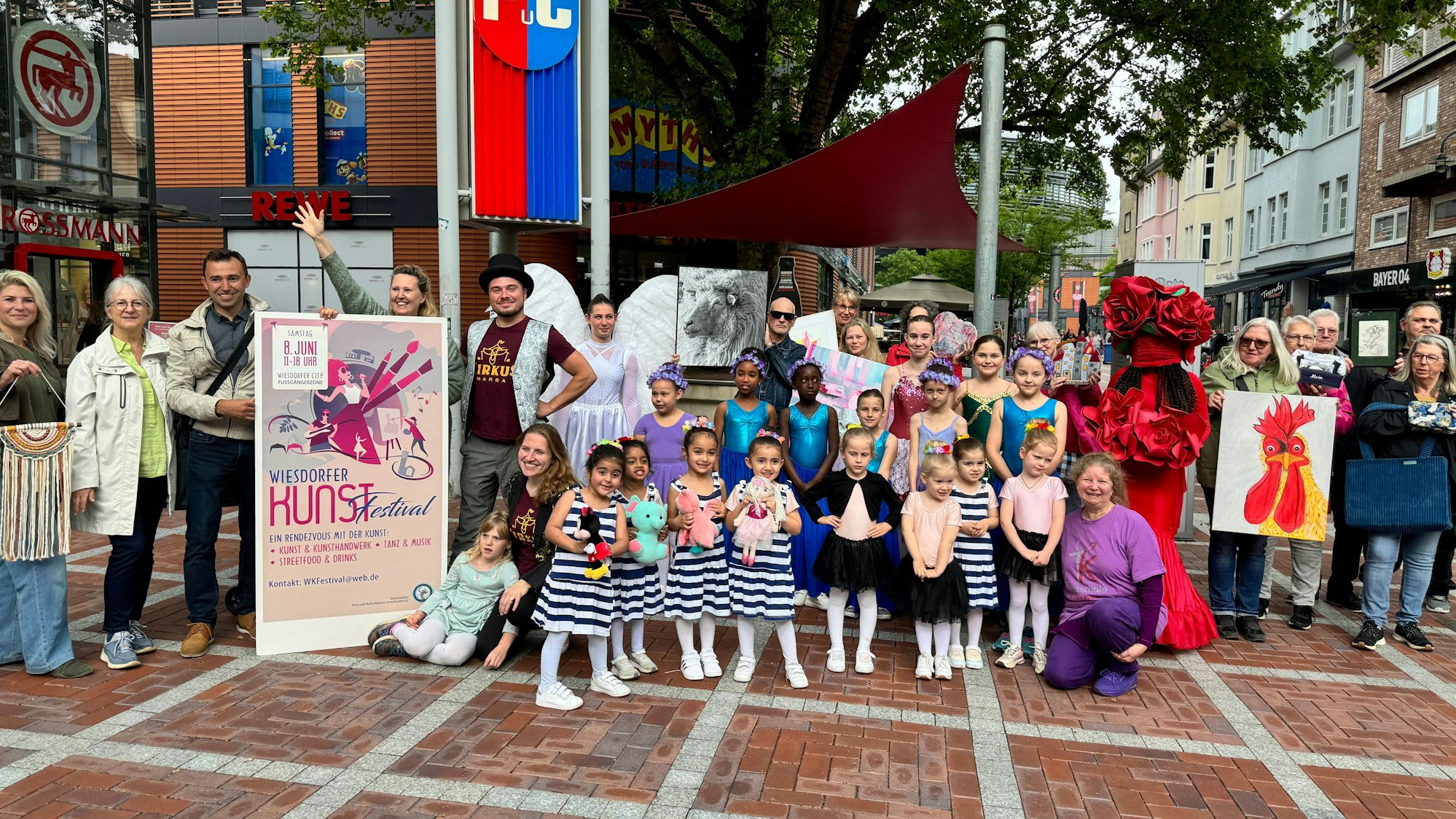 Erwachsene und Kinder stehen mit Plakat in der Wiesdorfer Fußgängerzone