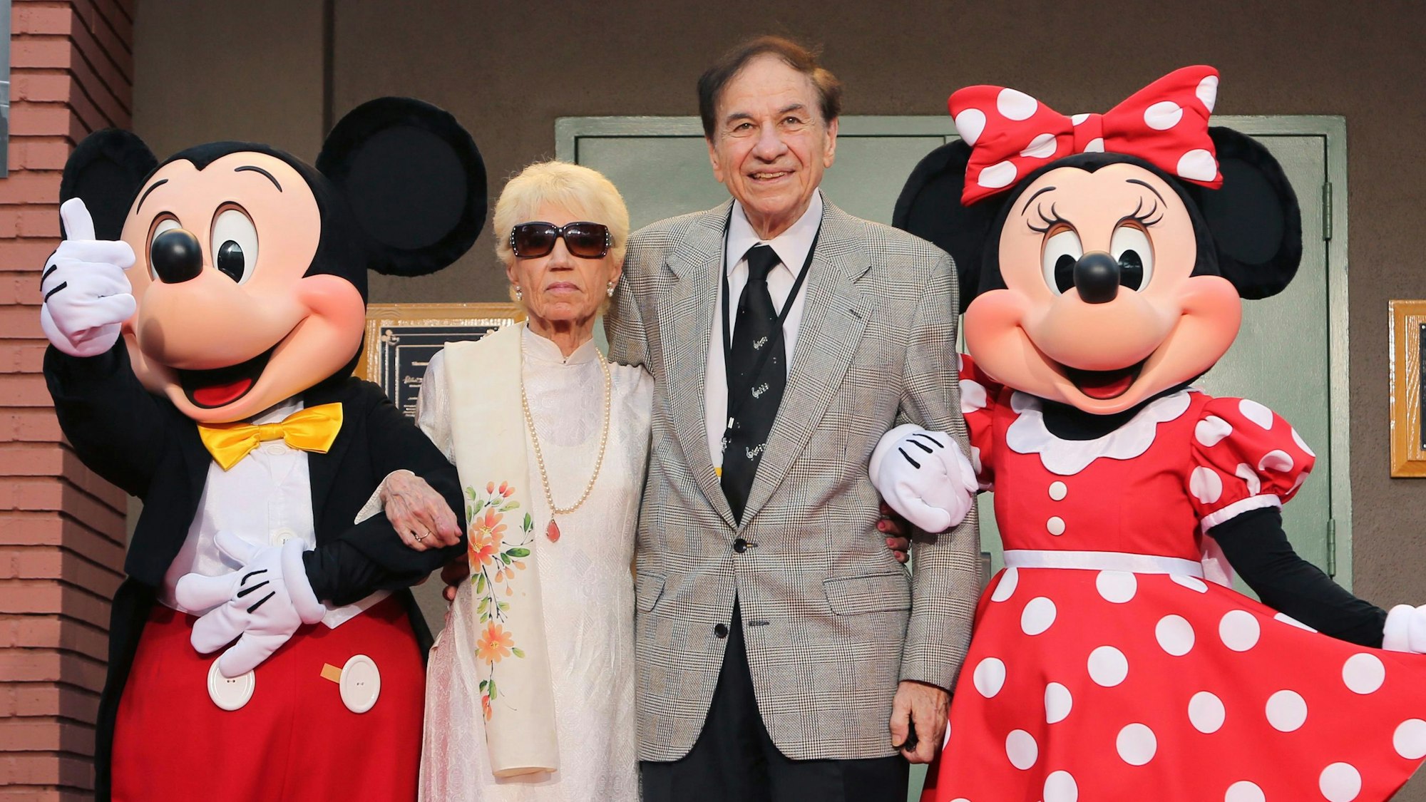 30.07.2018, USA, Burbank: Mickey Mouse, von links, Elizabeth Gluck, Richard M. Sherman und Minnie Mouse posieren für ein Foto bei der Feier zu Ehren der Sherman-Brüder mit der Umbenennung der Disney Studios Soundstage A bei der Weltpremiere von Disneys "Christopher Robin" in den Walt Disney Studios.