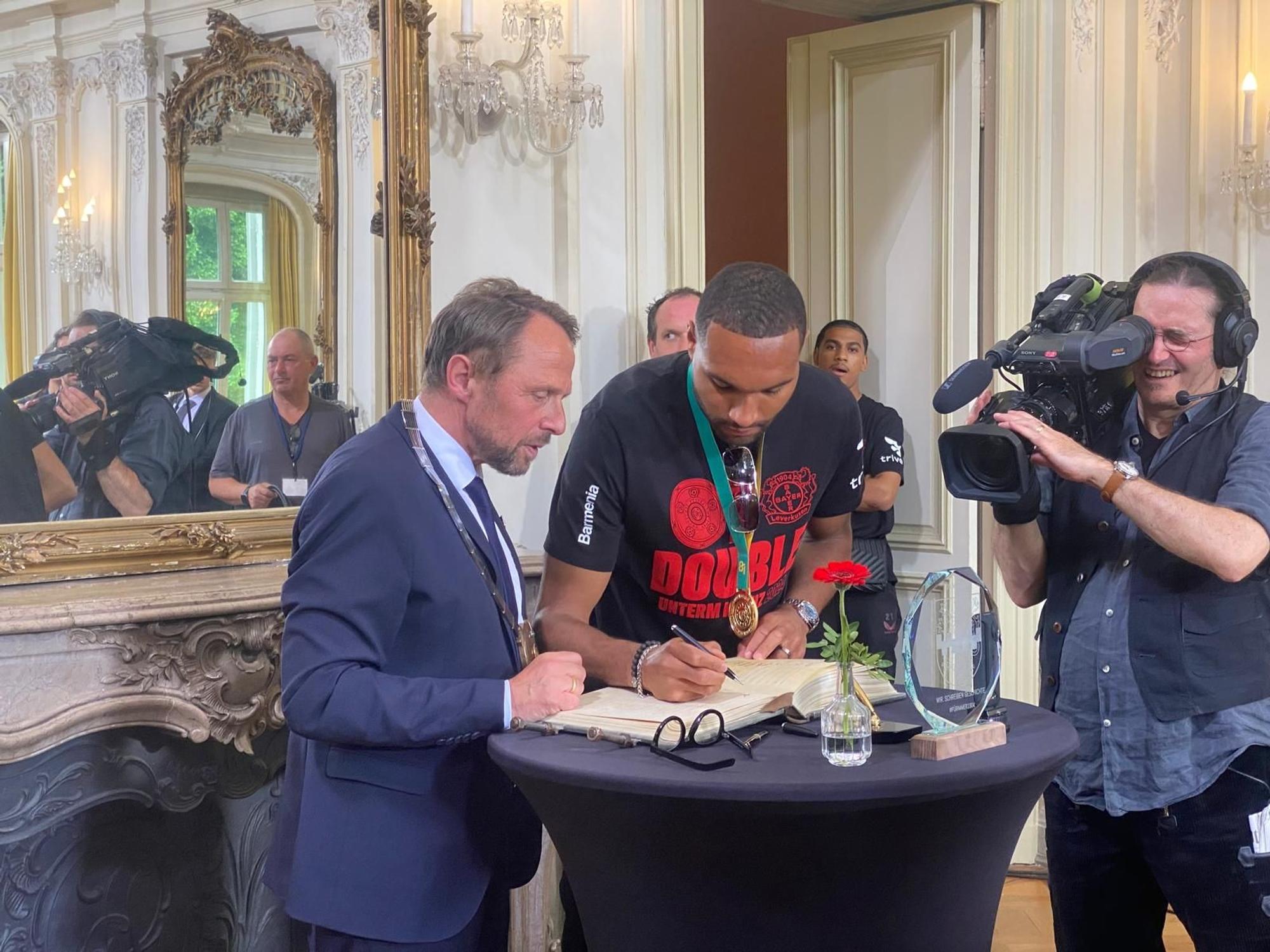 Jonathan Tah trägt sich ins goldene Buch ein.